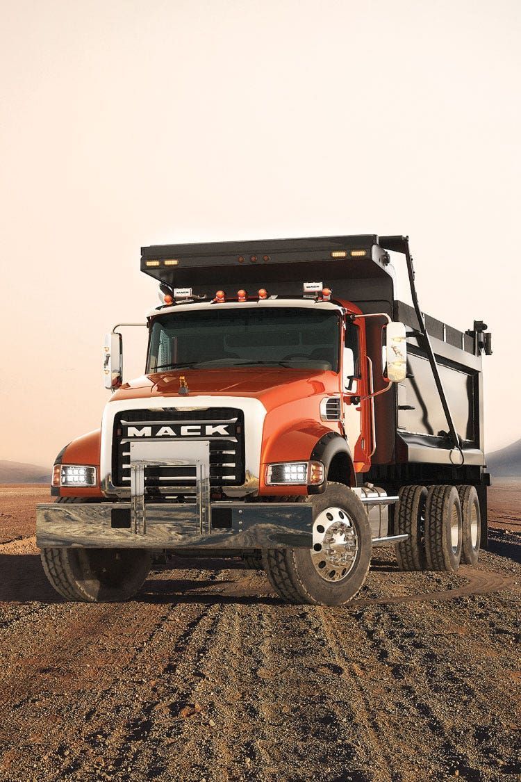 A red dump truck is parked in a dirt field.