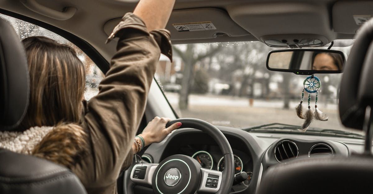 A woman is driving a car with her arms in the air.