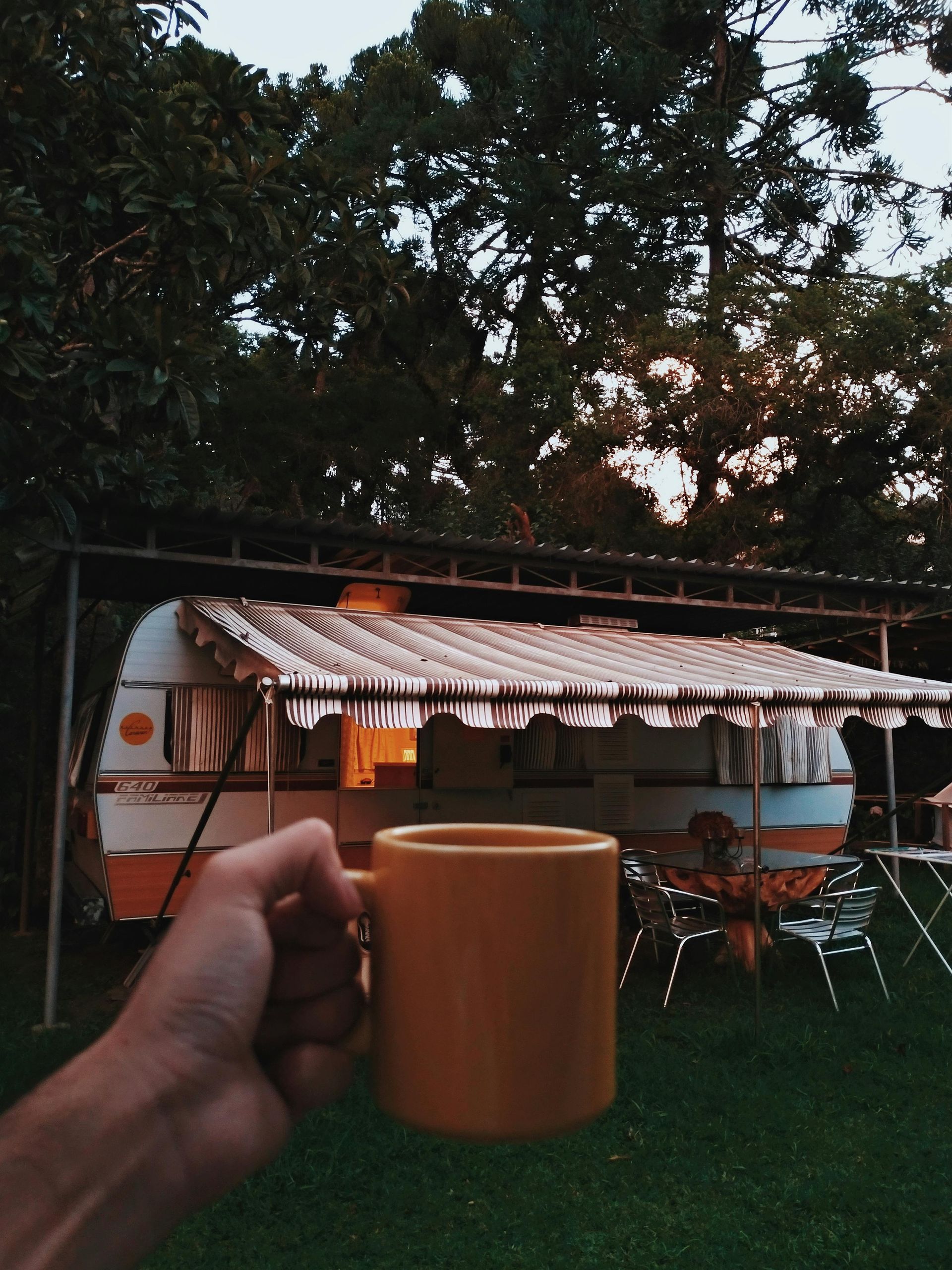 A person is holding a yellow mug in front of a trailer