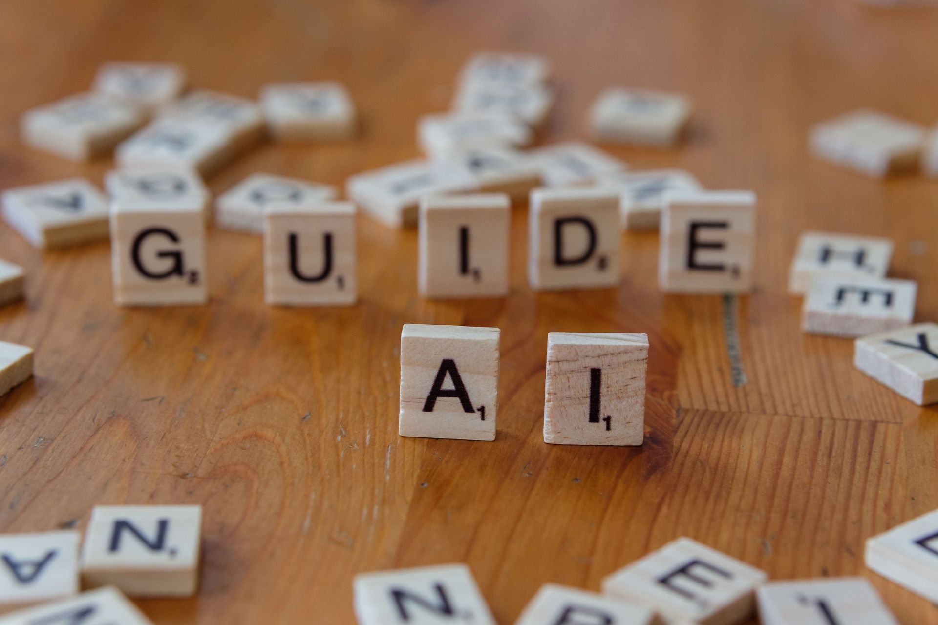 Scrabble-style letter tiles spelling “GUIDE AI” on a wooden table with scattered tiles around them