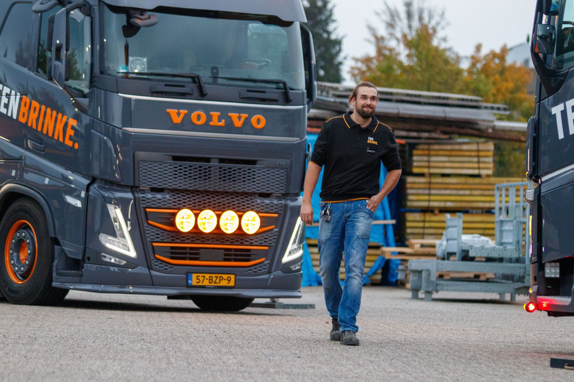 Man walking in front of a black Volvo truck at a construction site