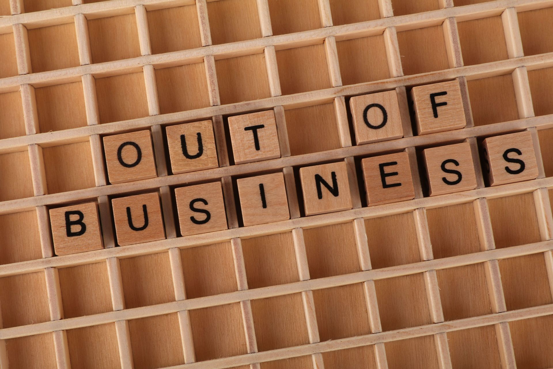 Tiles spelling “OUT OF BUSINESS” on a wooden letter board.