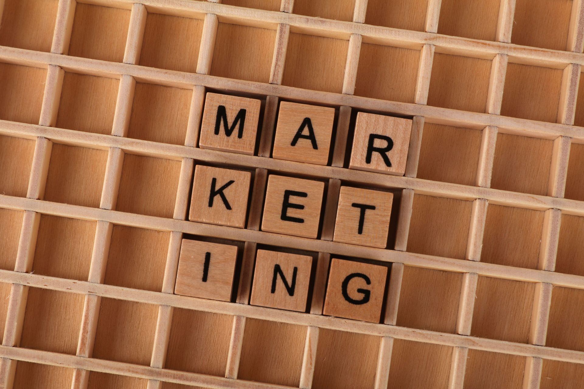 Scrabble tiles spelling “MARKETING” on a wooden lattice background
