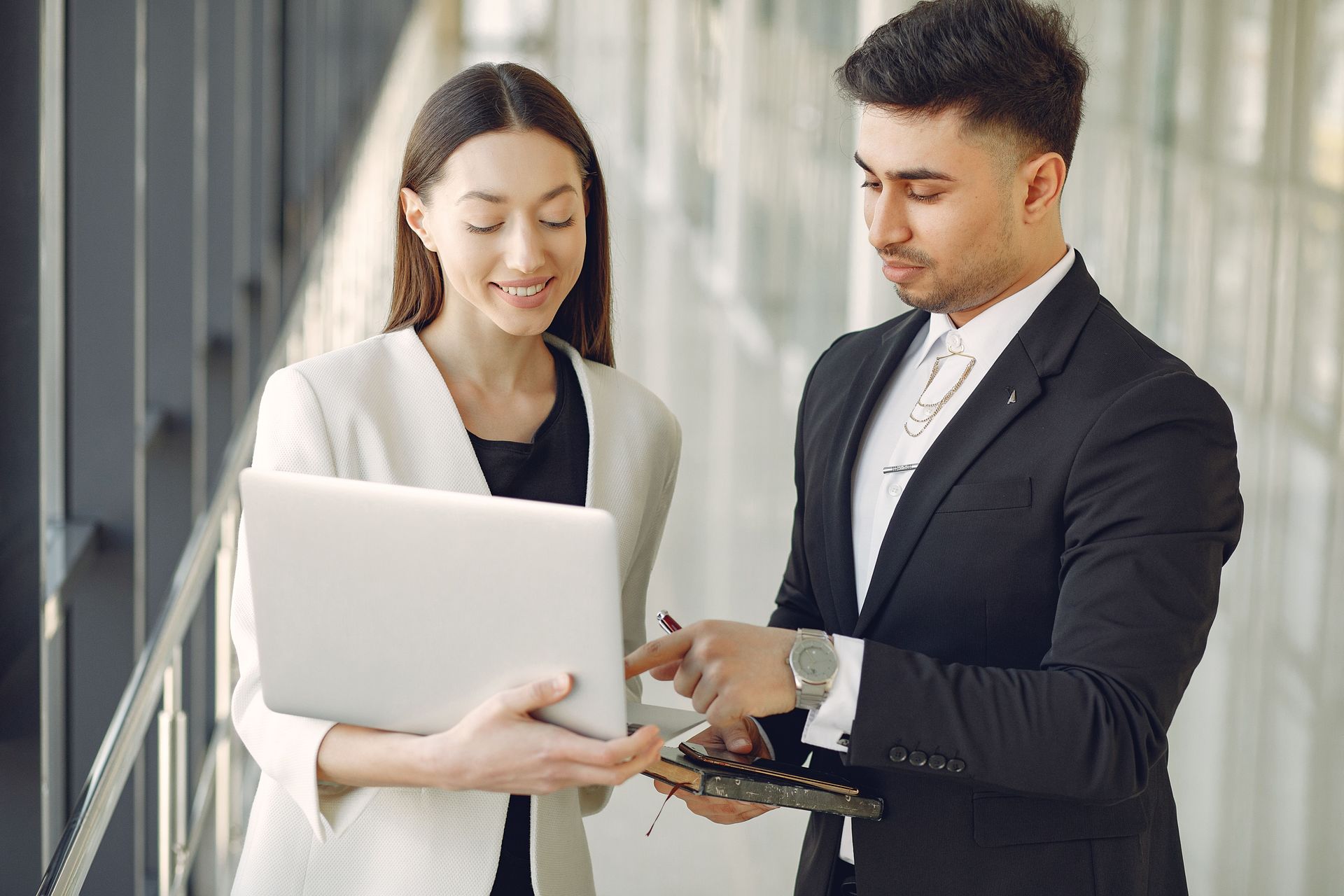 Two professionals discussing a laptop in a bright office setting