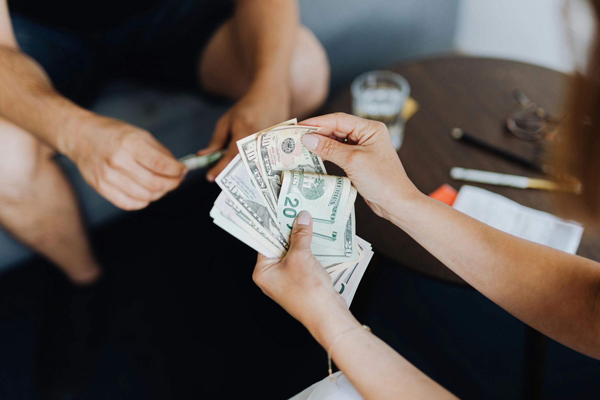 Hands exchanging cash, person holding a stack of bills and handing them to another.