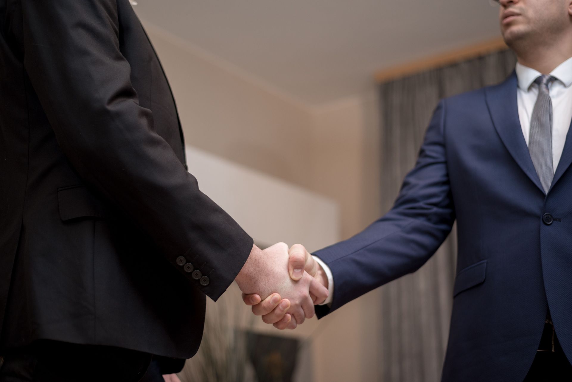 Two people in suits shaking hands in a formal office setting