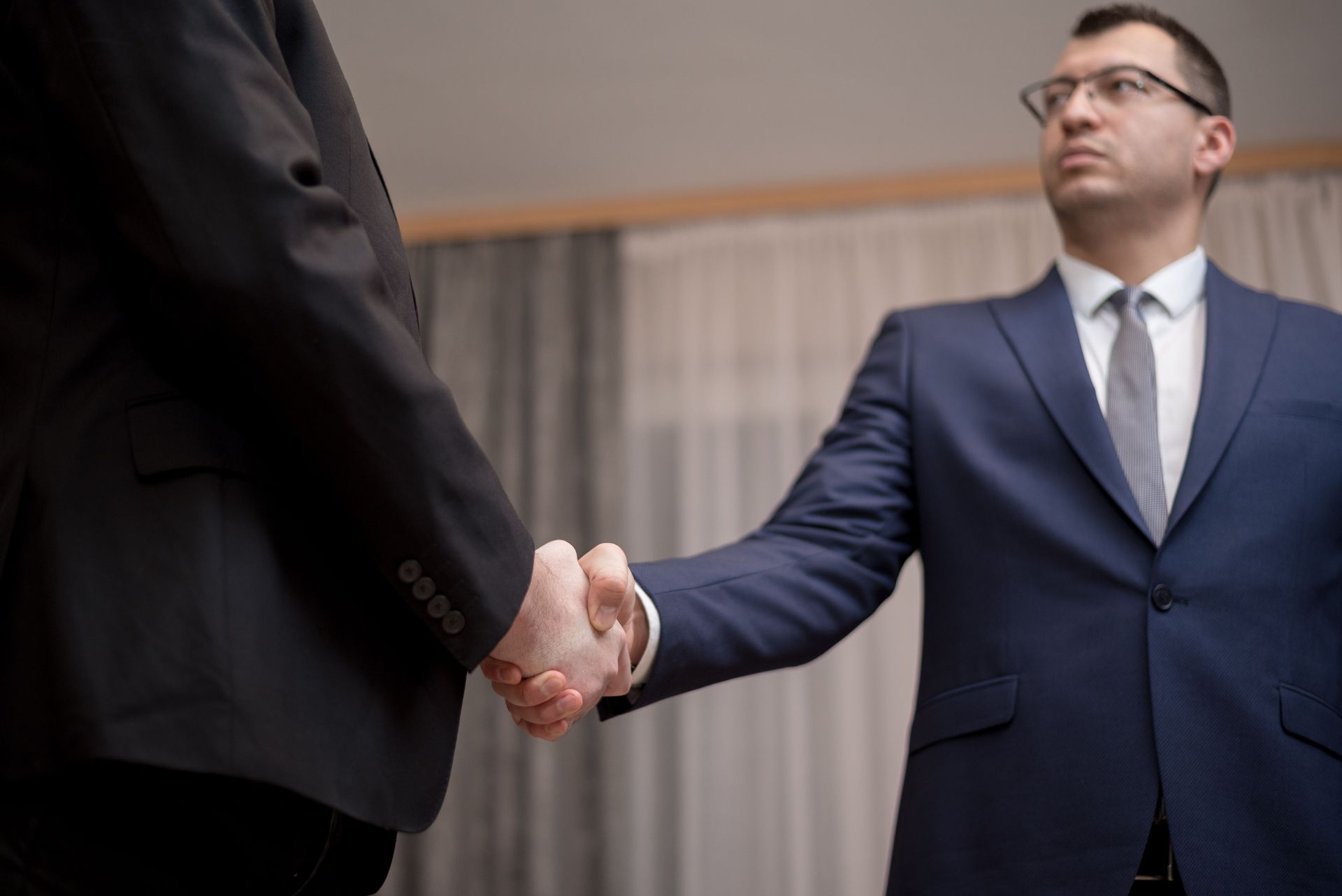 Two businessmen in suits shaking hands during a meeting indoors