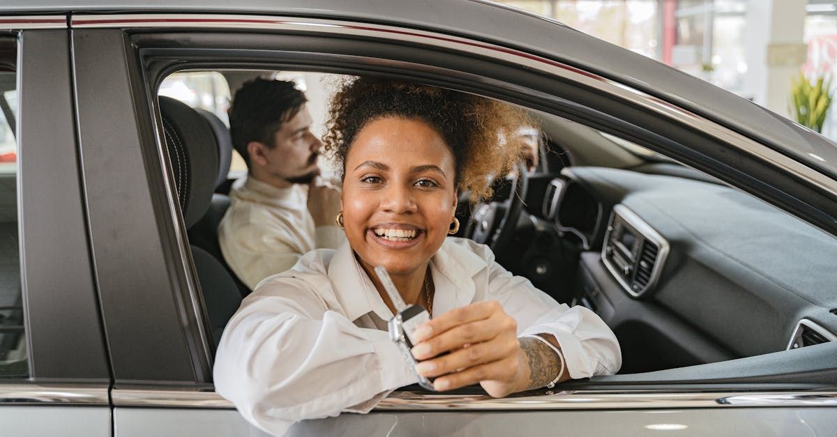 A woman is sitting in a car holding a car key.