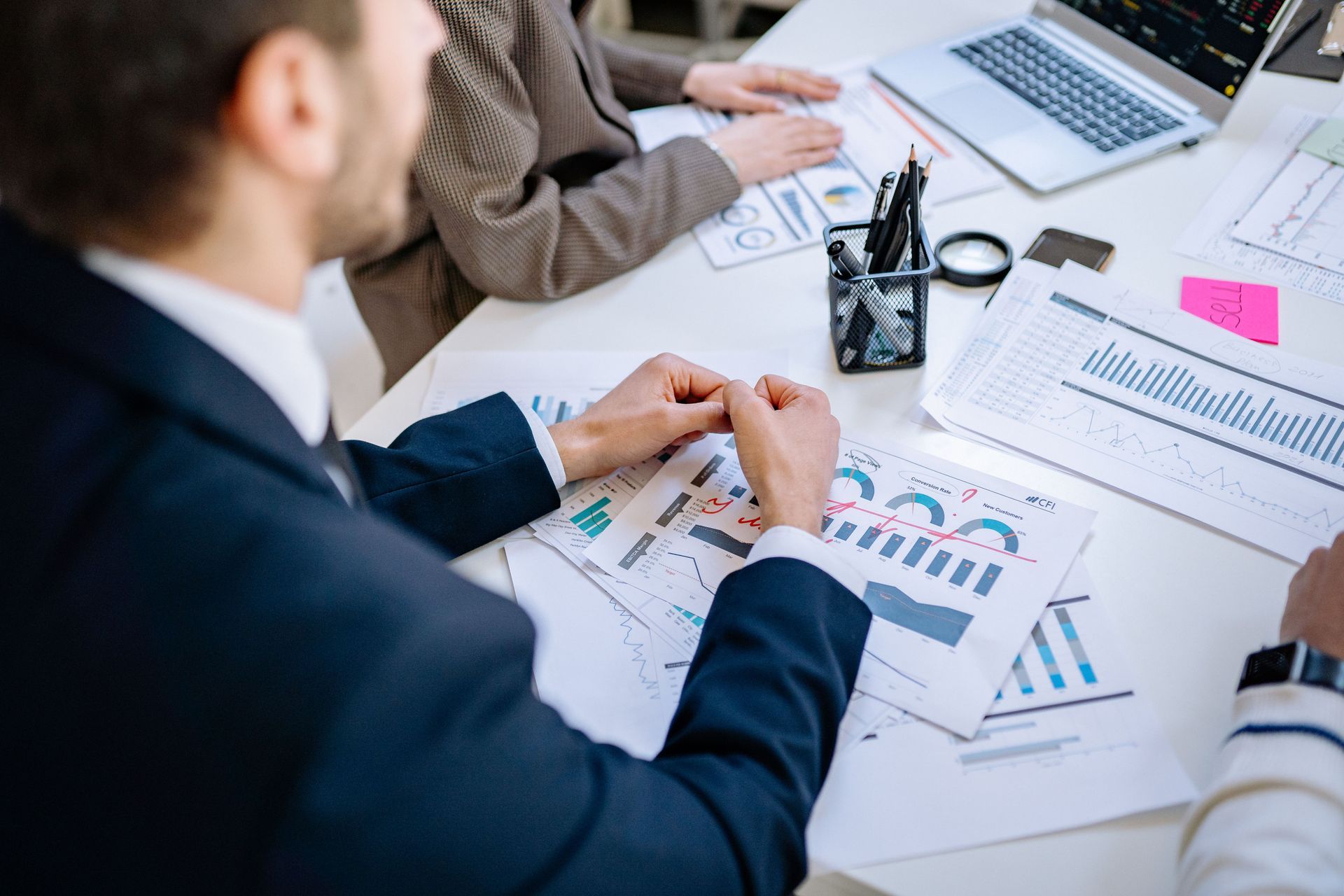 Business team reviewing charts and graphs at a meeting table with a laptop and documents