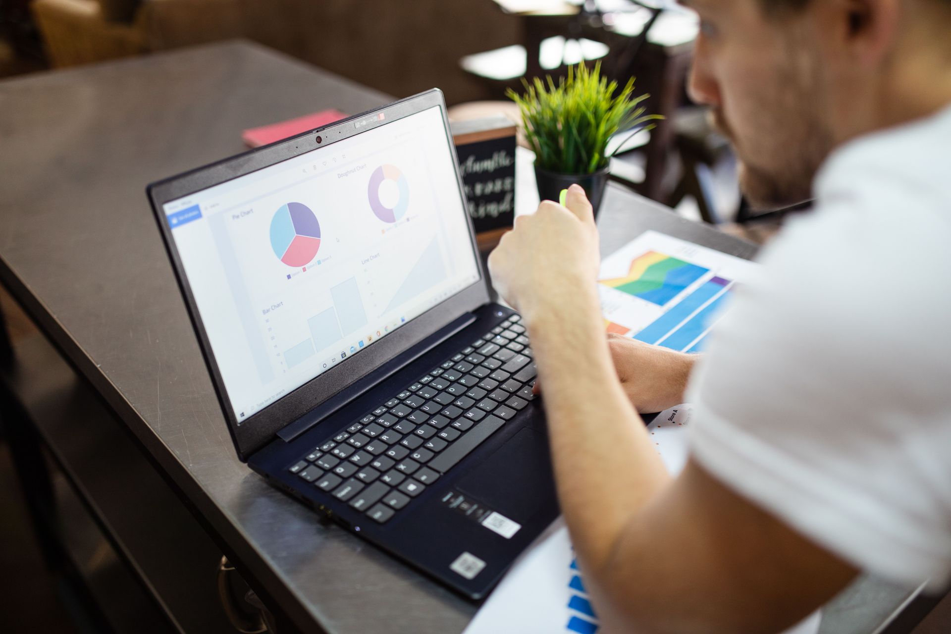 Person using a laptop with charts on screen during a meeting at a table
