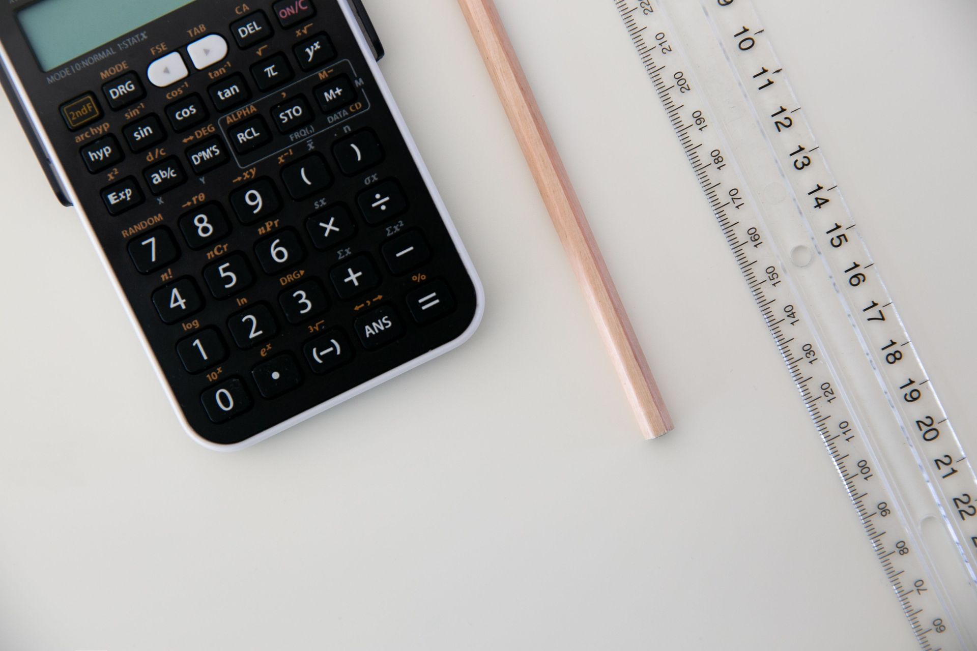 Calculator, pencil, and ruler on a white desk
