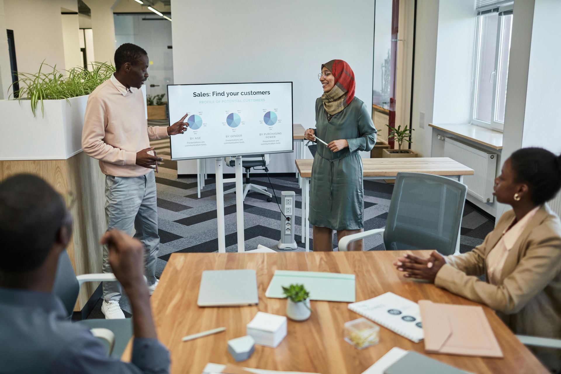 Colleagues in a meeting room presenting charts on a screen around a table