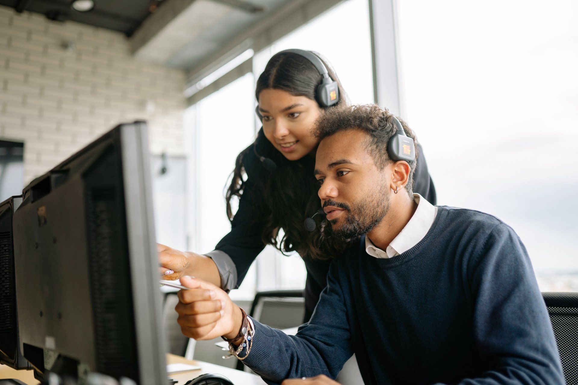 A man and a woman are looking at a computer screen.