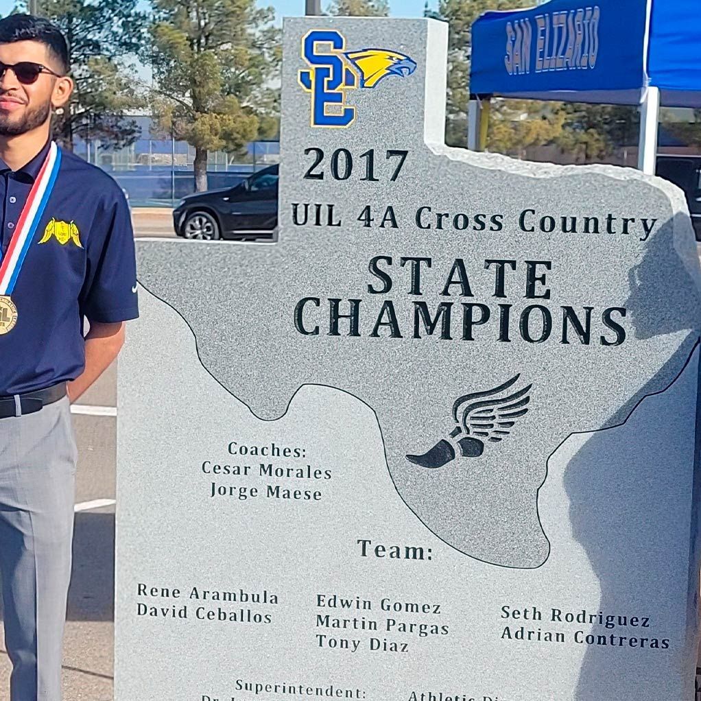 A man is standing in front of a texas state champions sign.