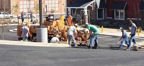 Road construction crew paving asphalt on a street with a paver and workers in safety vests