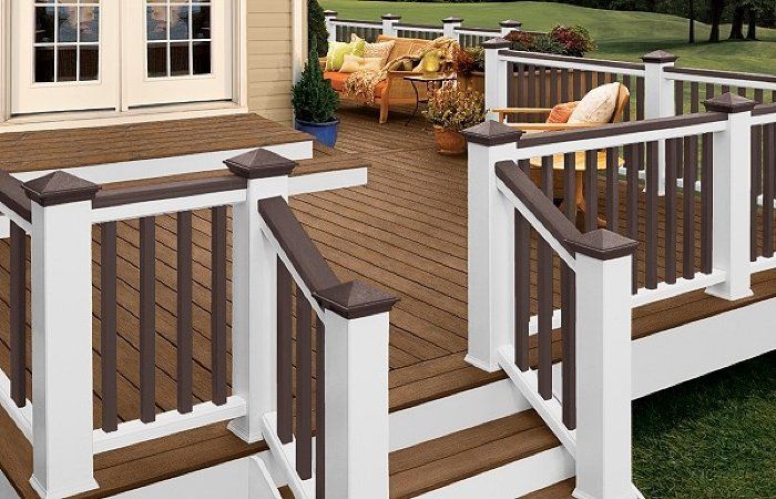 Backyard deck steps with white railings and dark wood handrails leading to a patio door