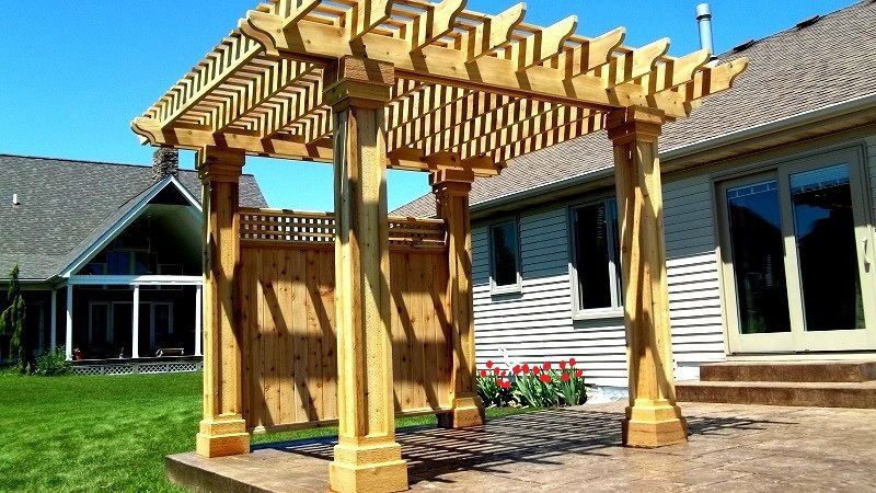 Wooden gazebo in a colorful flower garden with lush green trees in the background