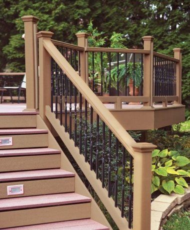 Outdoor wooden stairs with tan railings and black iron balusters leading to a deck. Outdoor wooden stairs with tan railings and black iron balusters leading to a deck.