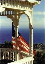 American flag on a white porch overlooking the ocean at sunset