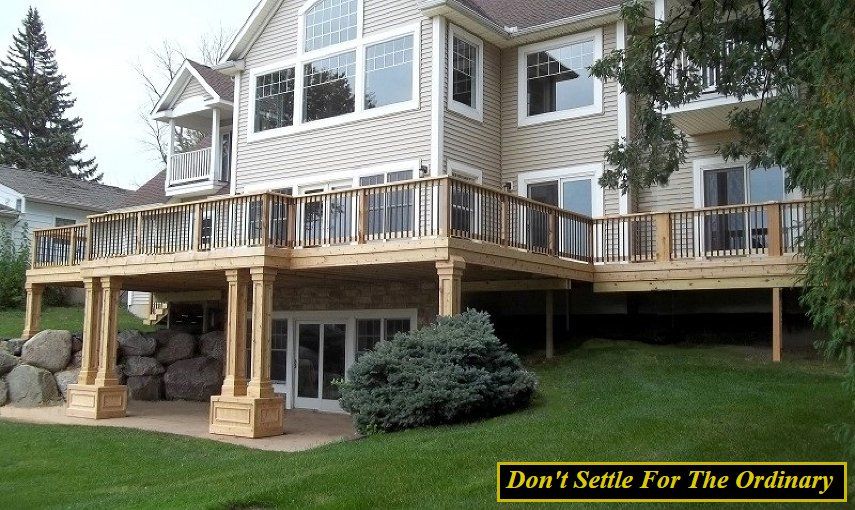 House with raised wooden deck and stone pillars over a green lawn