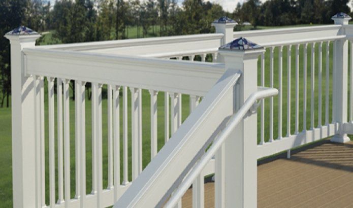 White deck railing with a sloped handrail overlooking a green yard and trees