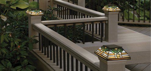 Outdoor staircase with beige railings and decorative glass-topped posts in a garden setting