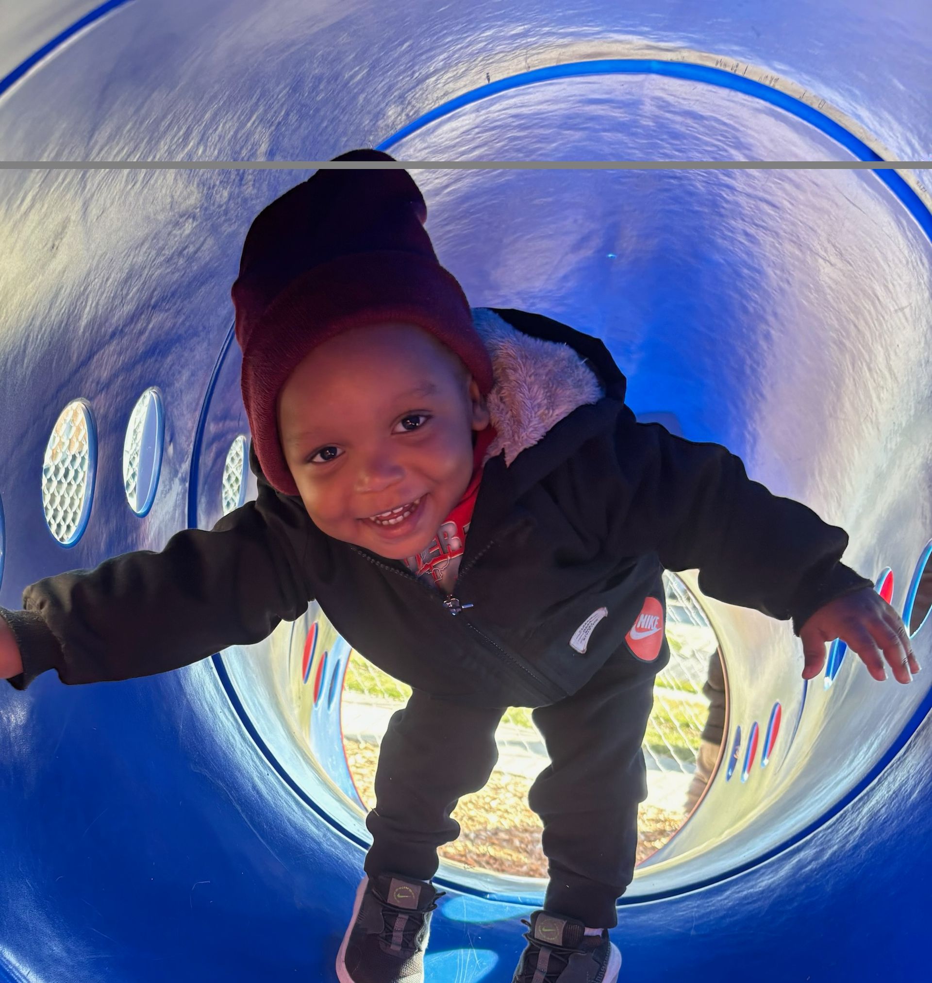 A little boy is playing in a blue tunnel