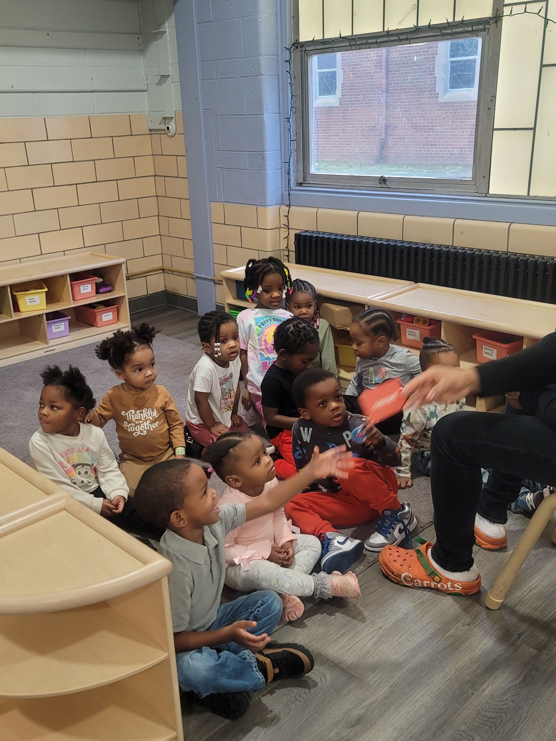 A group of children are sitting on the floor listening to a story.