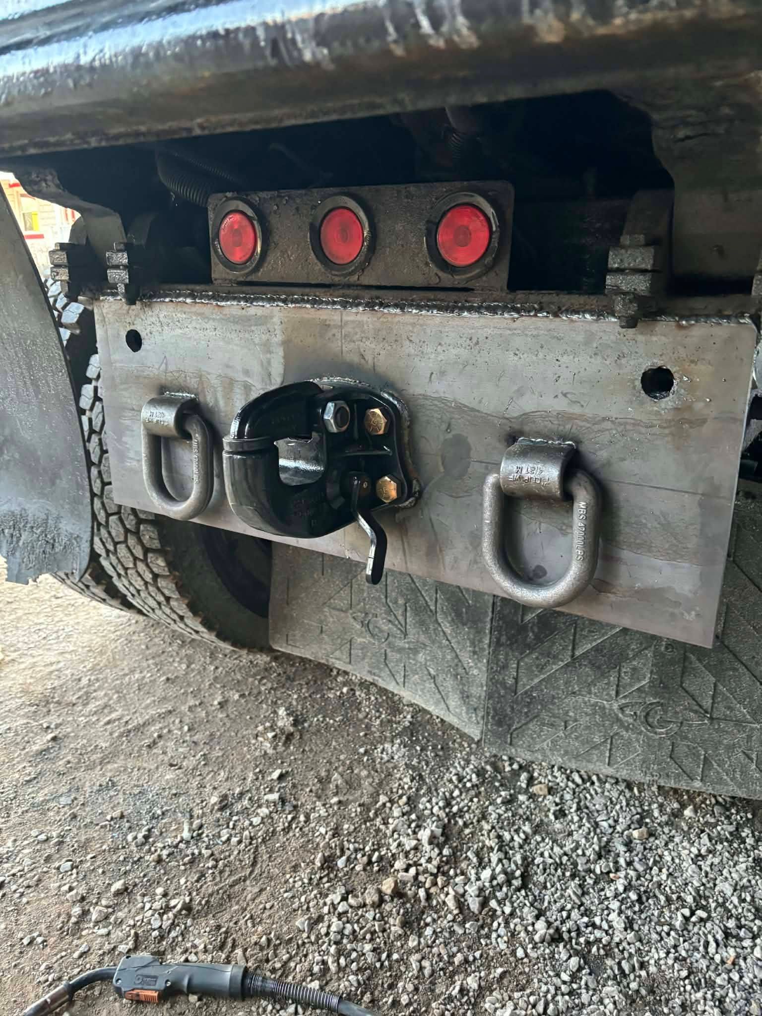 Truck's rear bumper with lights, towing hitch, and D-rings, likely for heavy-duty use.
