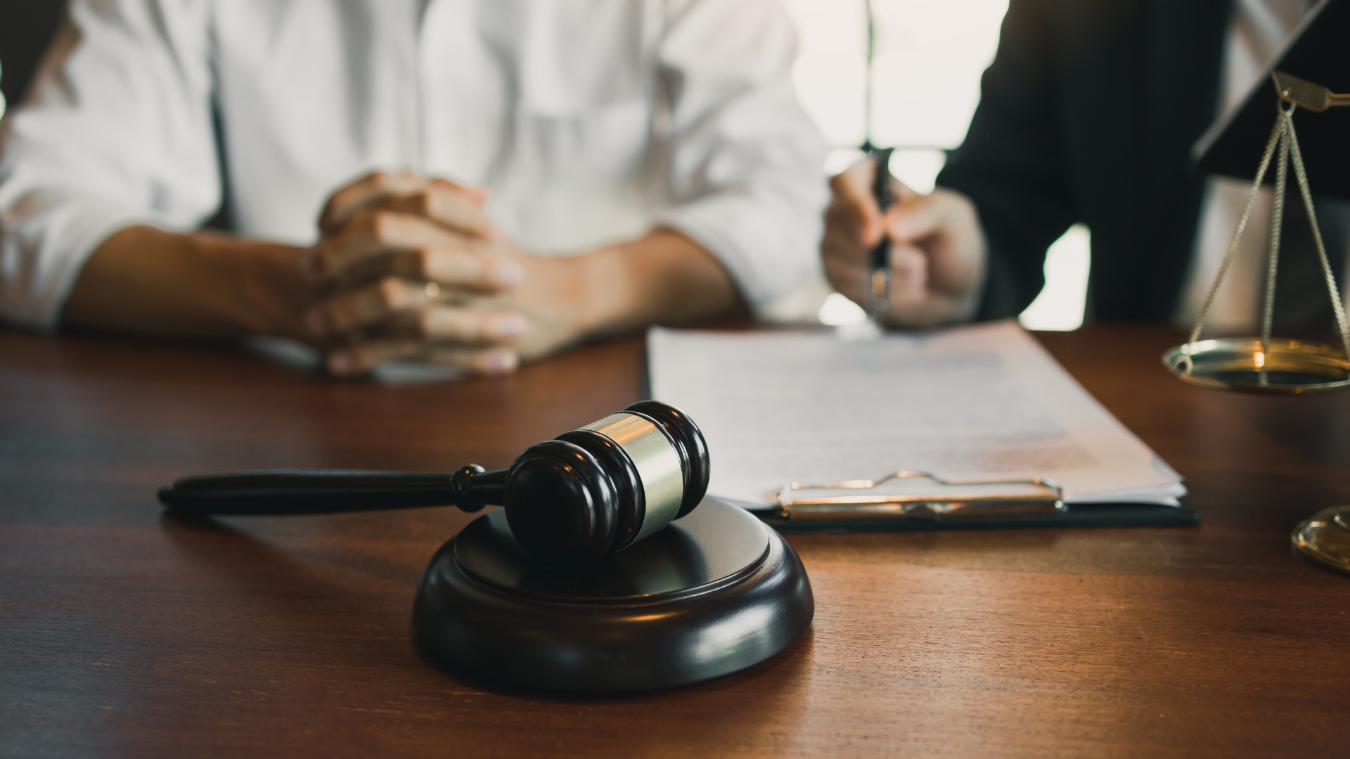 Judge’s gavel on desk with legal paperwork and blurred people in the background
