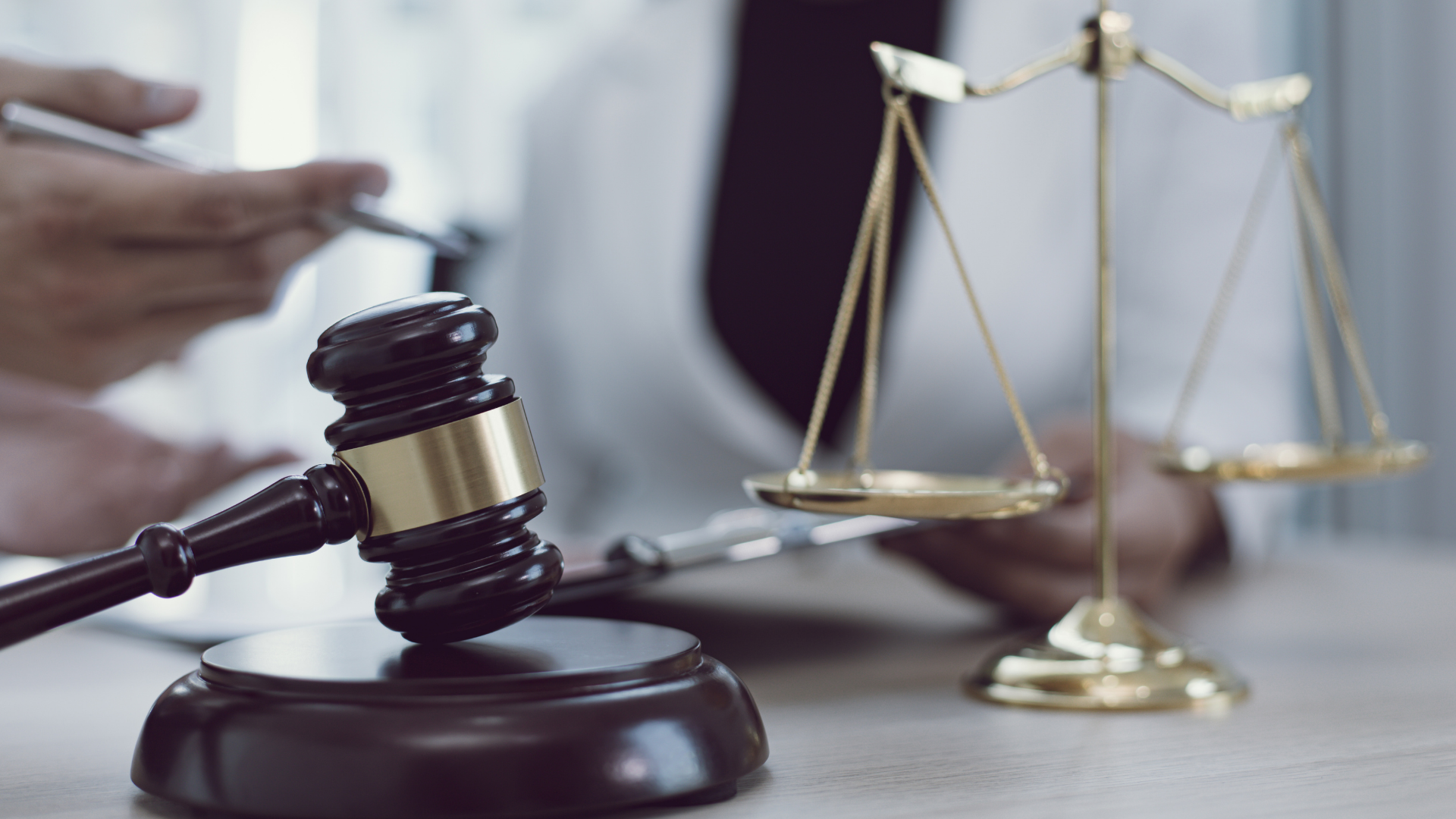 Judge’s gavel and scales of justice on a desk with blurred legal books in the background