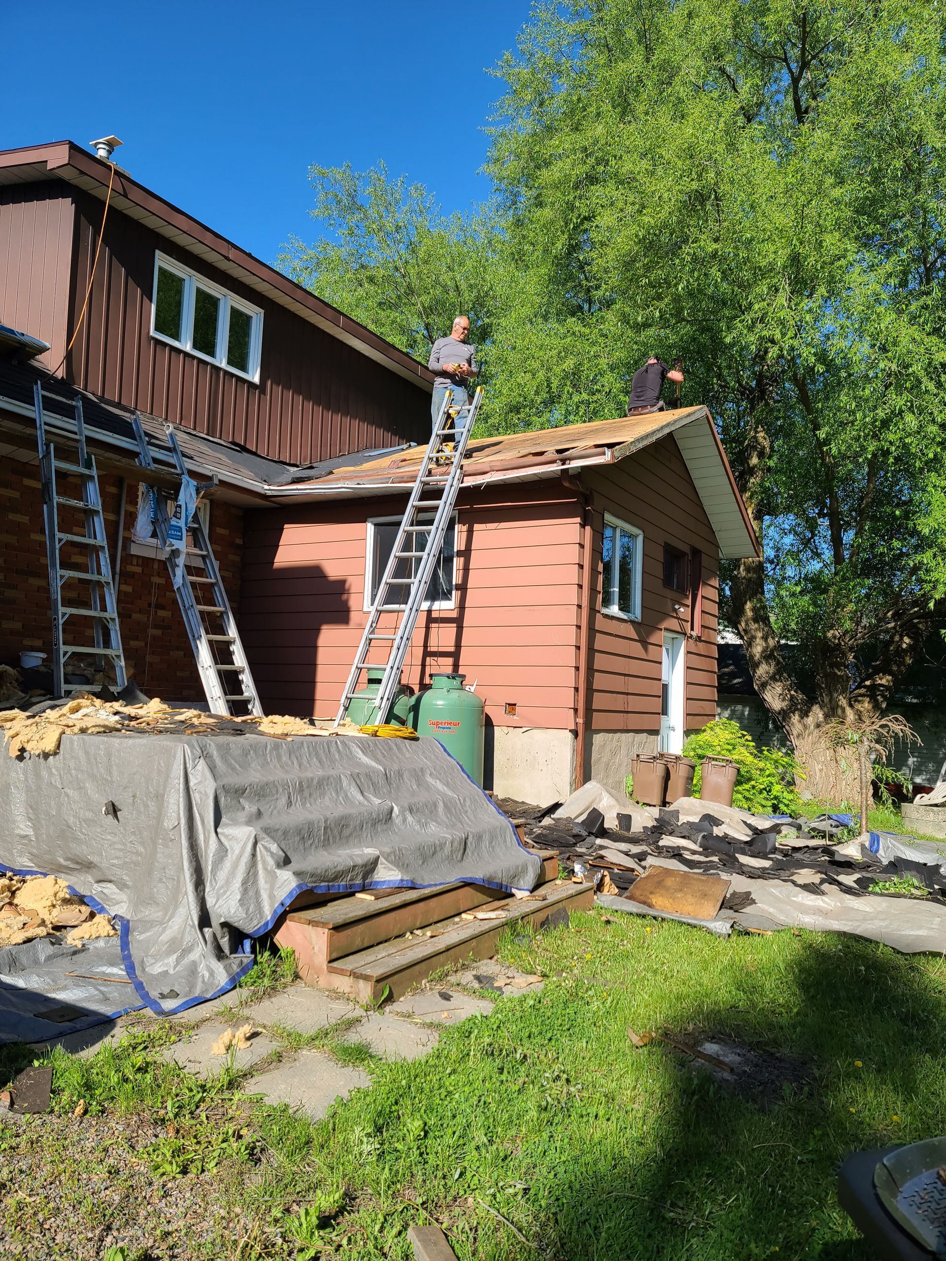 Two men are working on the roof of a house.