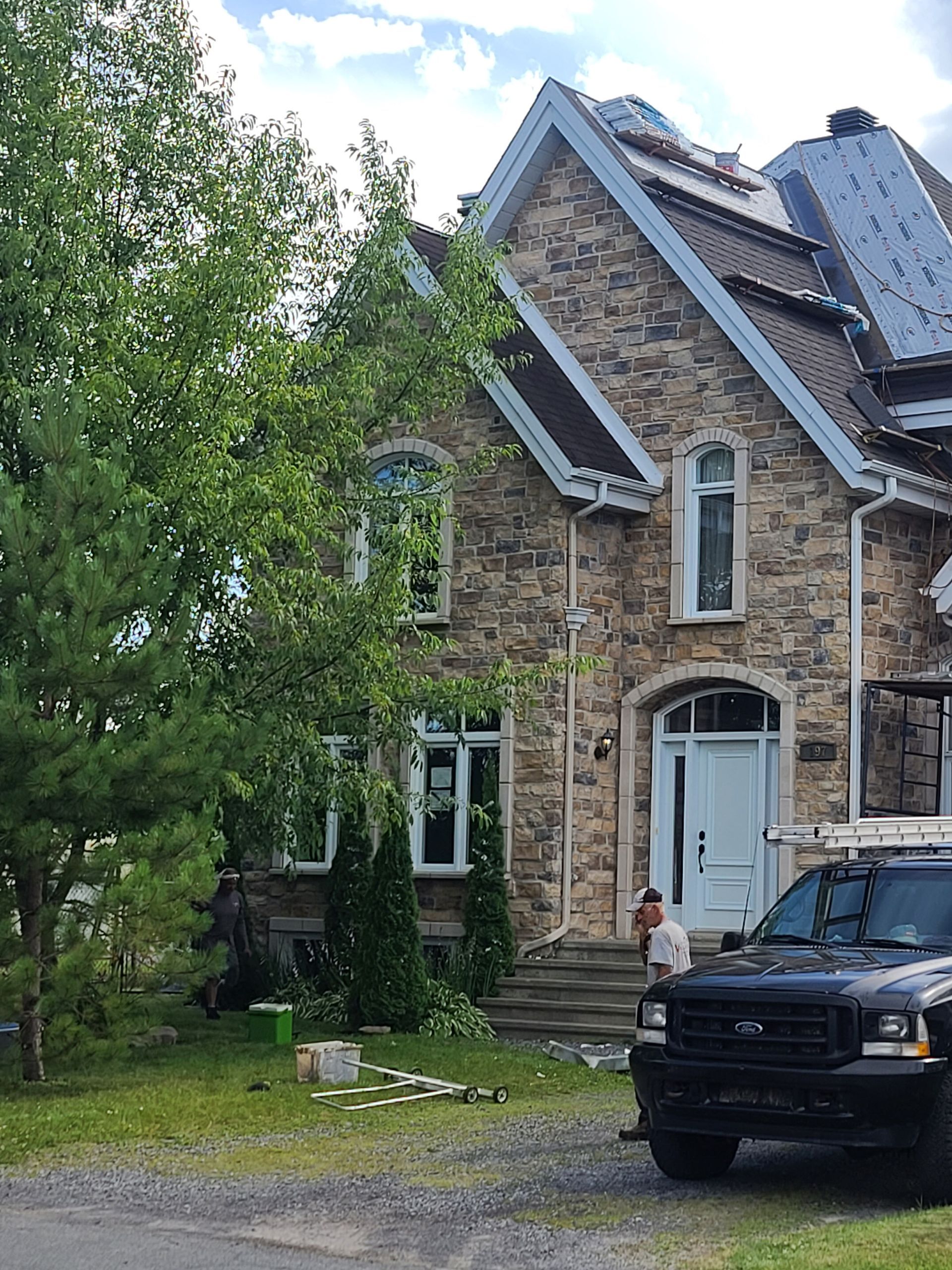 A truck is parked in front of a large stone house.