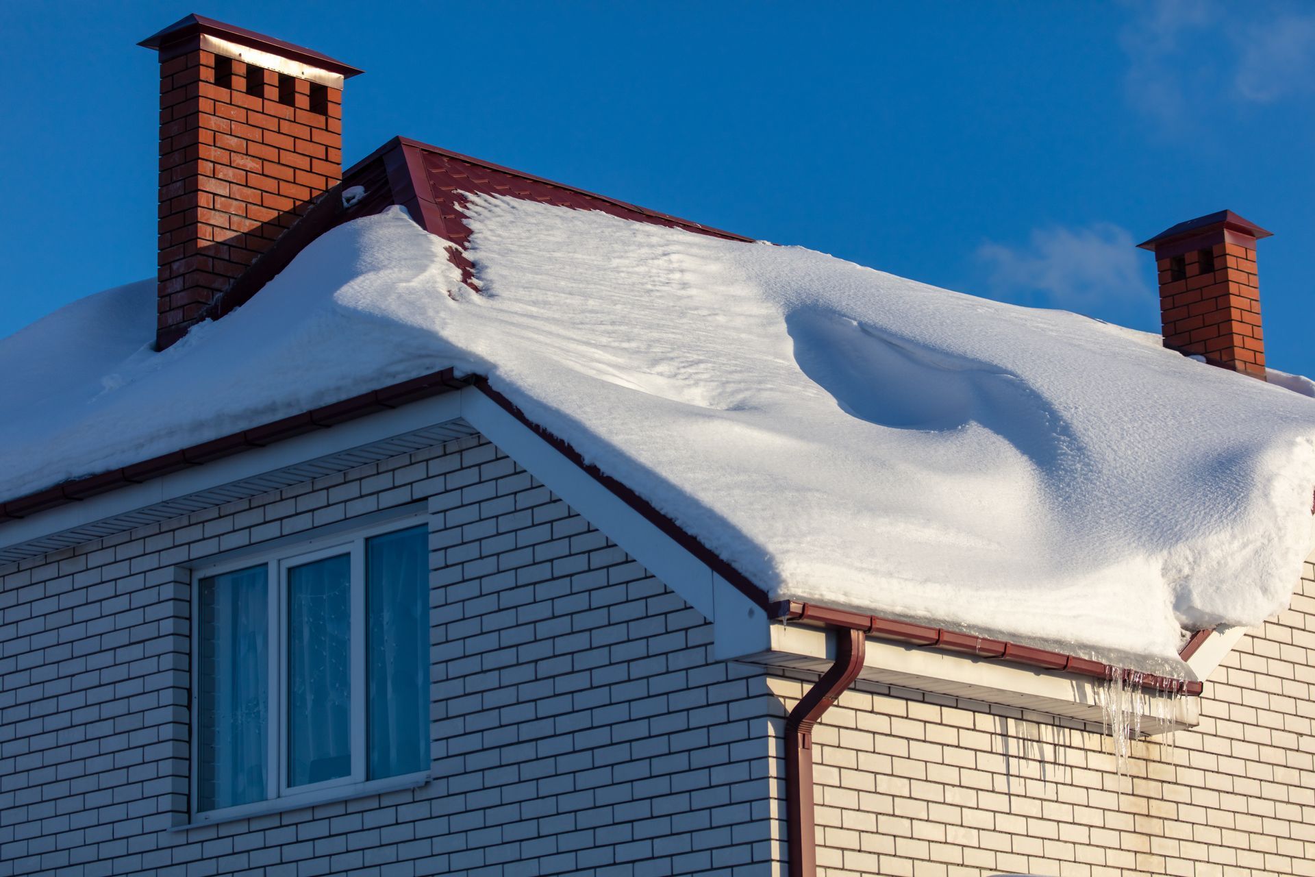 Une maison en briques blanches avec de la neige sur le toit