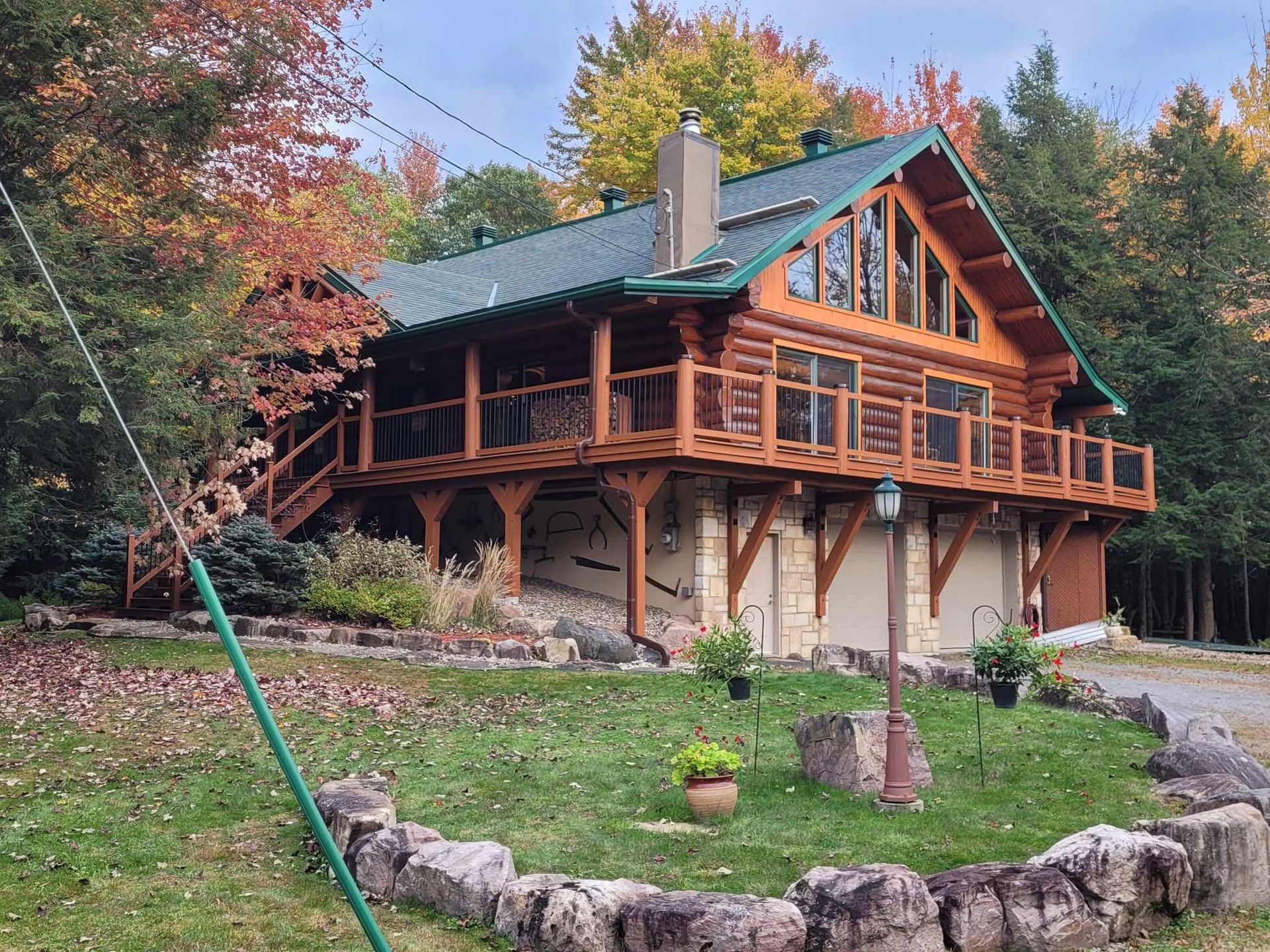 A large log cabin with a green roof is surrounded by trees.