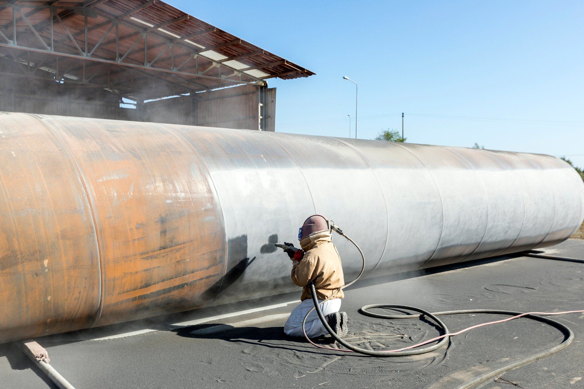 Man Working Sandblasting to The Large Pipe — Cornelia, GA — Dan's Painting LLC