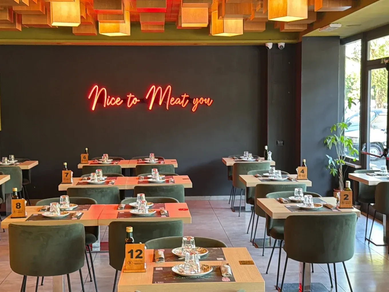 Elegante sala da pranzo di un ristorante con pareti scure, insegna al neon luminosa e tavoli ordinatamente apparecchiati