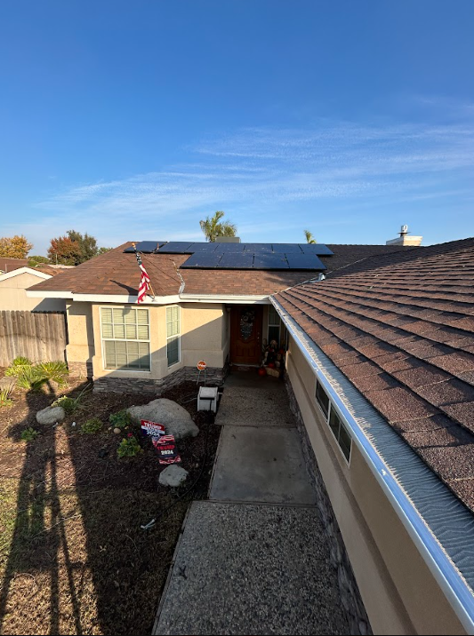 Person on a roof working near the edge against a bright blue sky