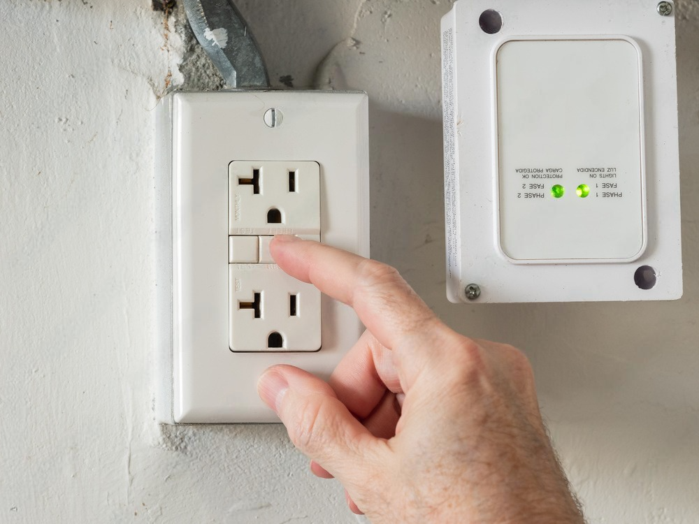 a person is plugging a device into an electrical outlet .