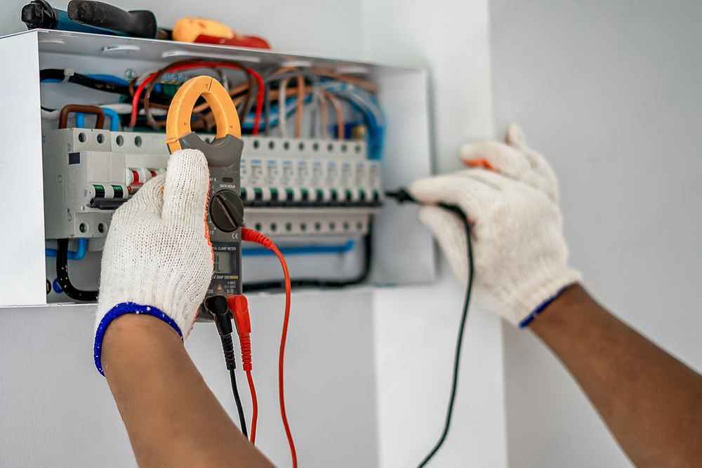 a person is using a clamp meter to test an electrical box .