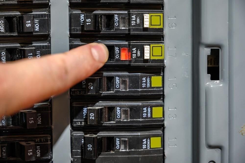 a person is pressing a button on a breaker box .