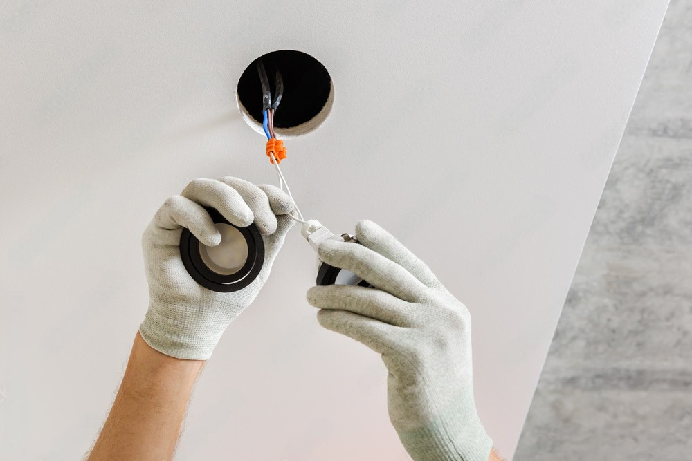 a person is installing a light fixture in a ceiling .