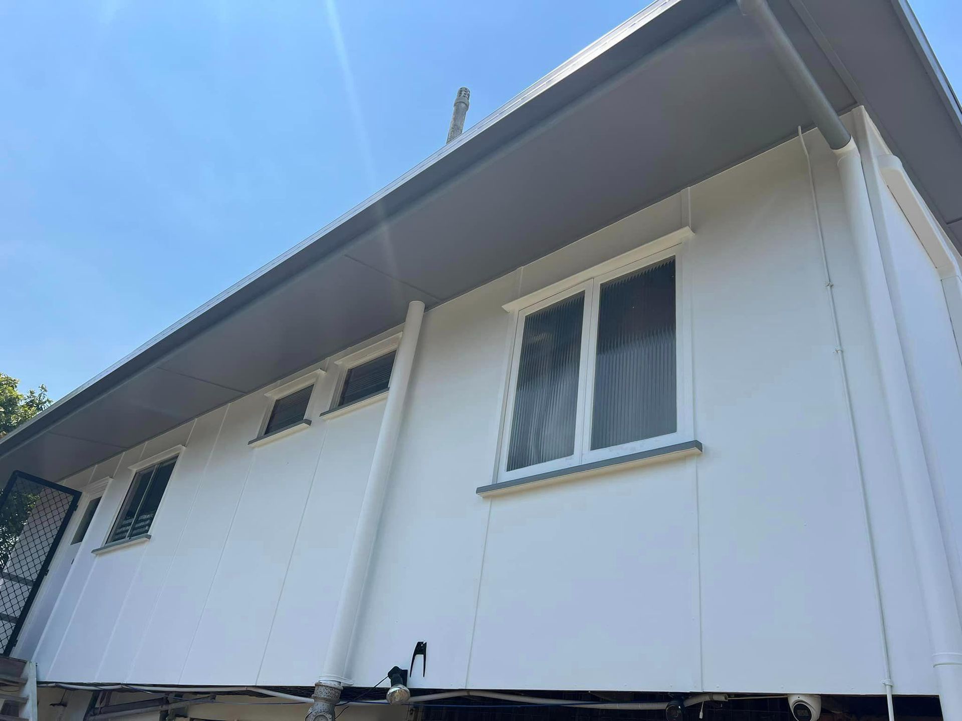 A White House with A Lot of Windows and A Blue Sky in The Background — Darren Smith Painting Pty Ltd in Rural View, QLD