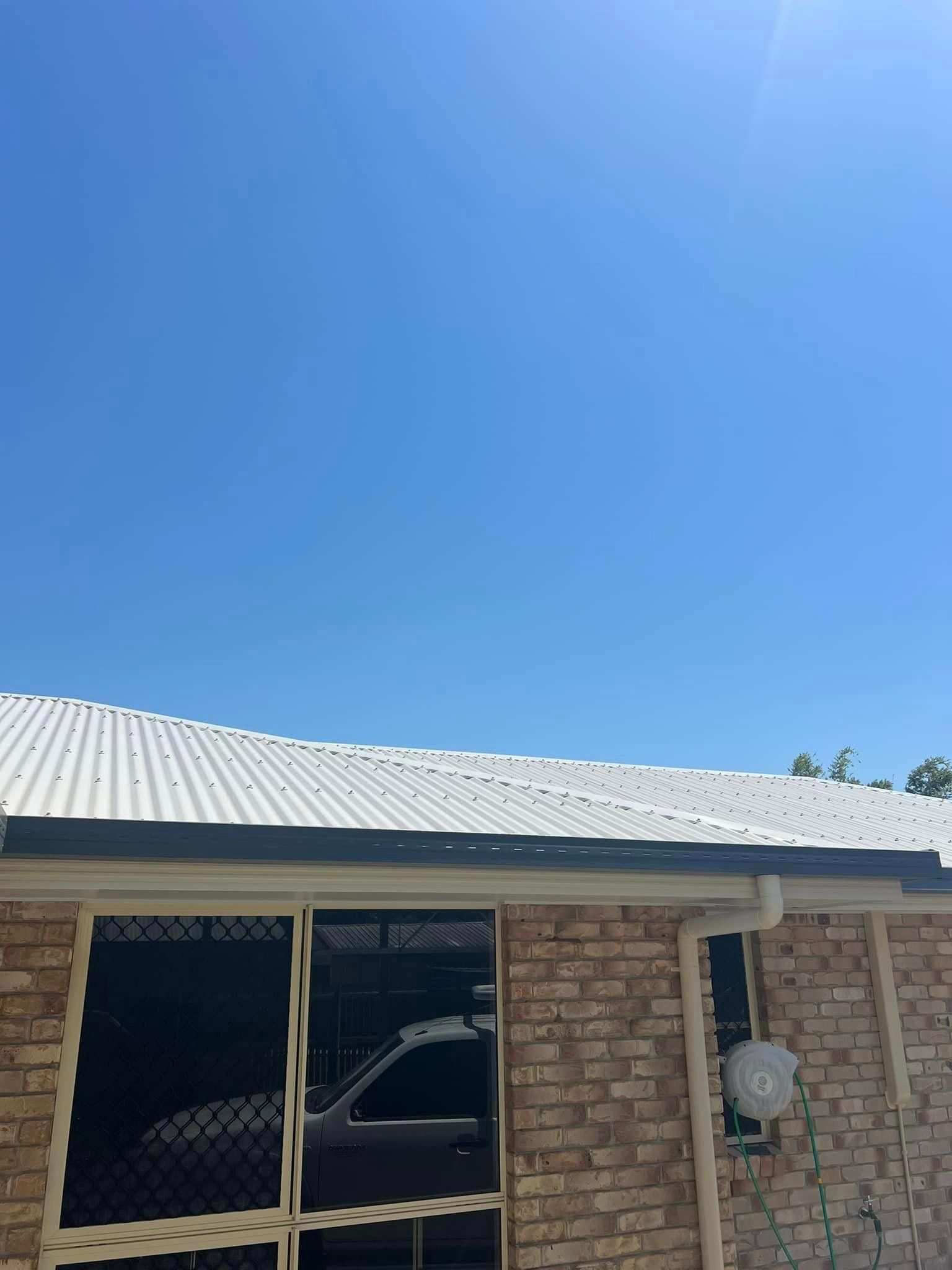A Brick House with A White Roof and A Blue Sky in The Background — Darren Smith Painting Pty Ltd in Northern Beaches, NSW