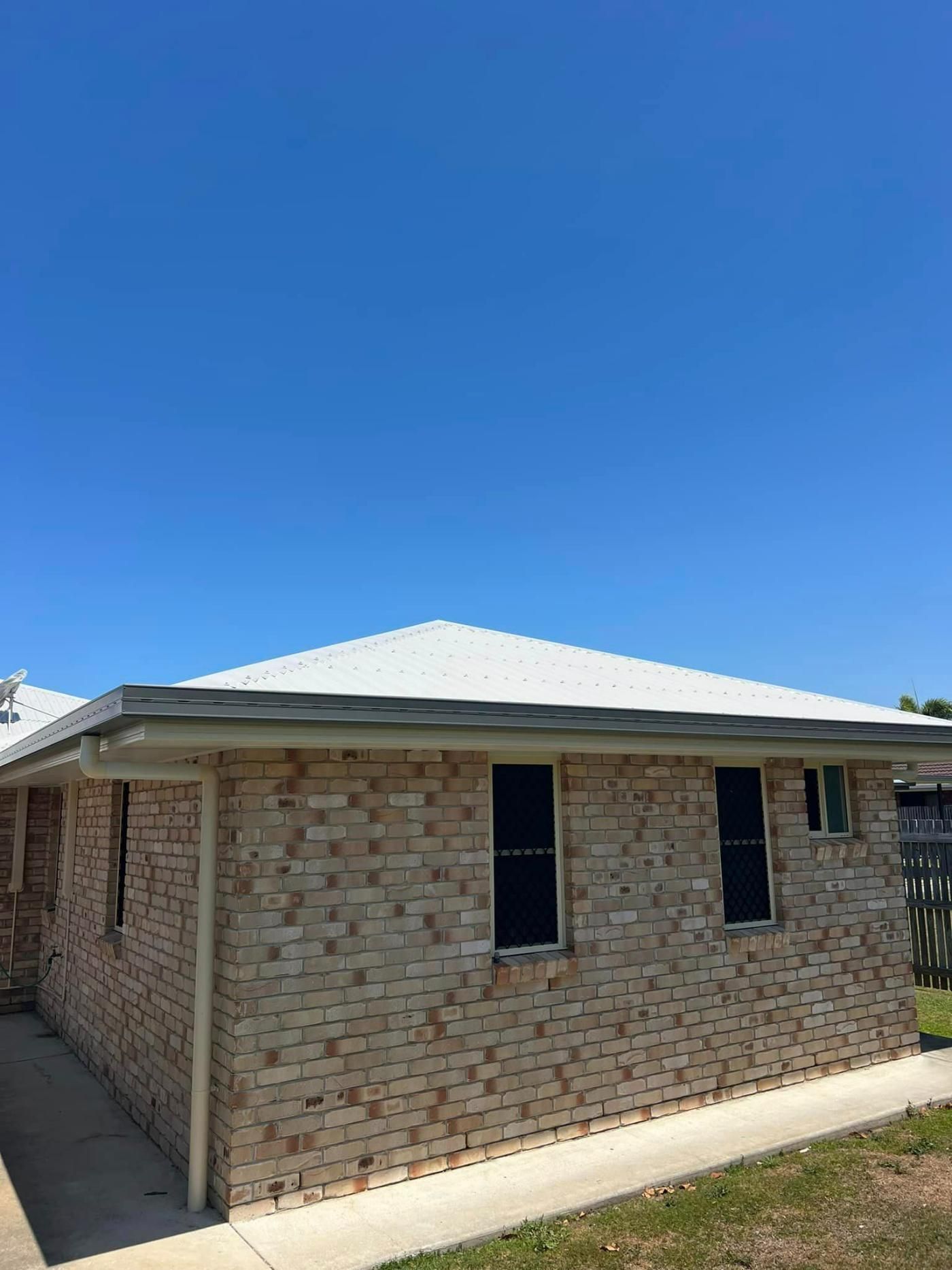 A Brick House with A White Roof and A Blue Sky in The Background — Darren Smith Painting Pty Ltd in Sarina, QLD