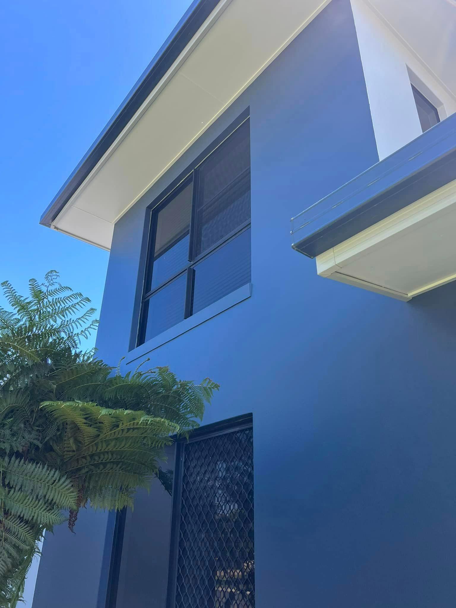 A Blue House with A Lot of Windows and A Blue Sky in The Background — Darren Smith Painting Pty Ltd in Northern Beaches, NSW