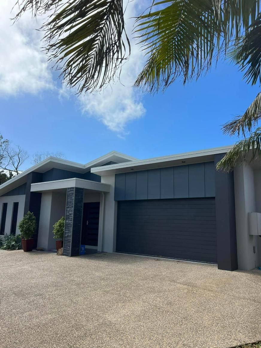 A Large House with A Garage and A Palm Tree in Front of It — Darren Smith Painting Pty Ltd in Sarina, QLD