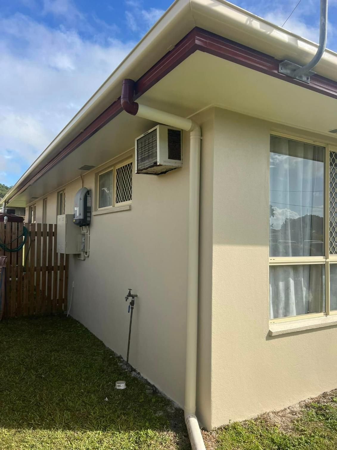 A White House with A Red Gutter and A White Air Conditioner on The Side of It — Darren Smith Painting Pty Ltd in Mirani, QLD