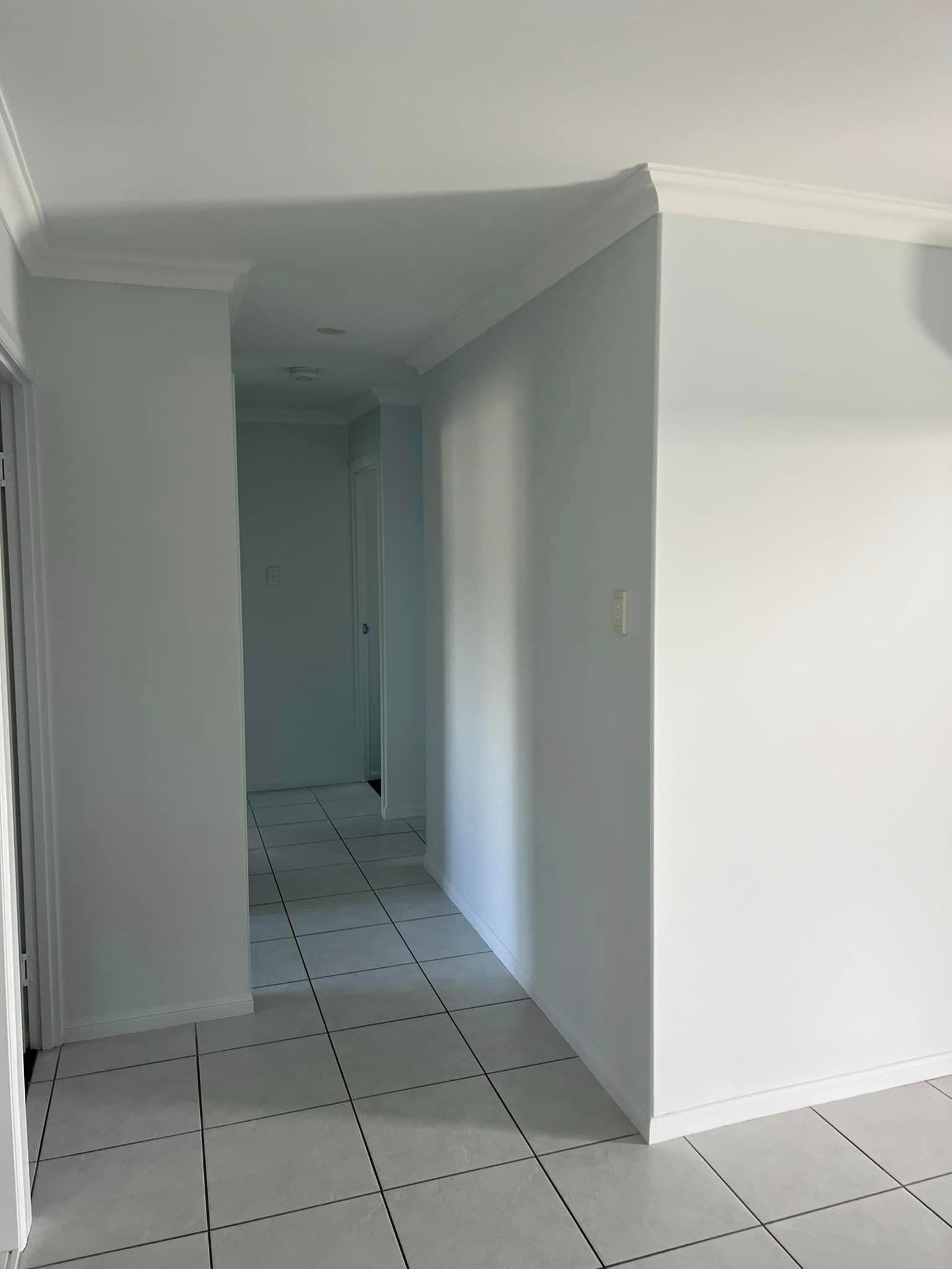 An Empty Hallway with White Tiles and White Walls in A House — Darren Smith Painting Pty Ltd in Sarina, QLD