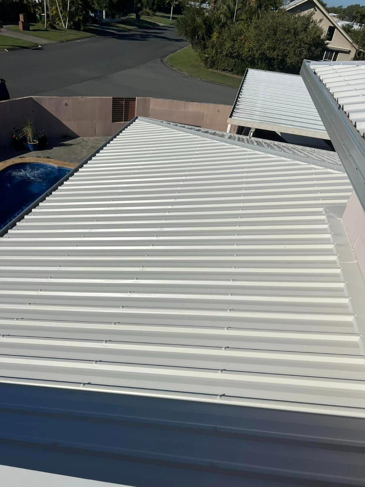 A White Metal Roof with A Swimming Pool in The Background — Darren Smith Painting Pty Ltd in Sarina, QLD